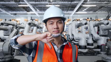 trabajador que muestra desaprobación de los robots industriales en la fábrica