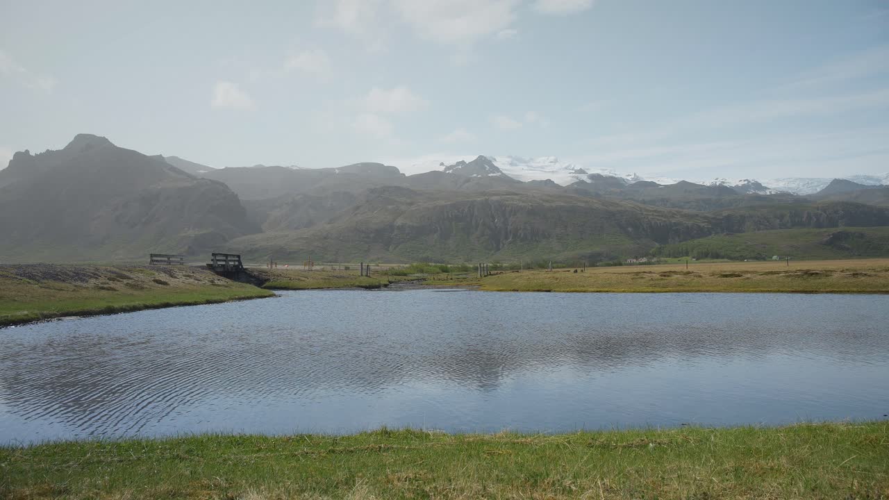un tranquilo lago de montaña en un día soleado con montañas cubiertas de nieve en el horizonte