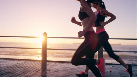 two athletic woman running outdoors slow motion on promenade at sunset near ocean enjoying evening run