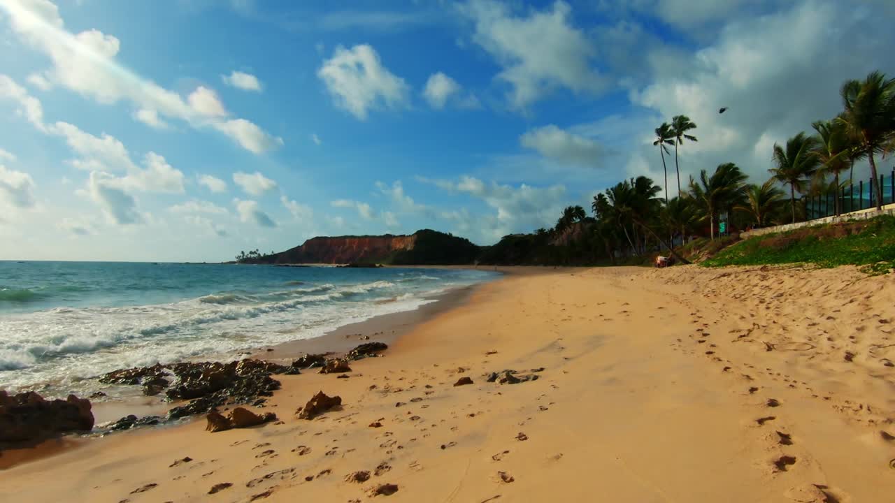 caminhando por uma praia incrivelmente bela com areia dourada, água azul e palmeiras na praia tropical de tabatinga perto de joão pessoa na paraíba, brasil