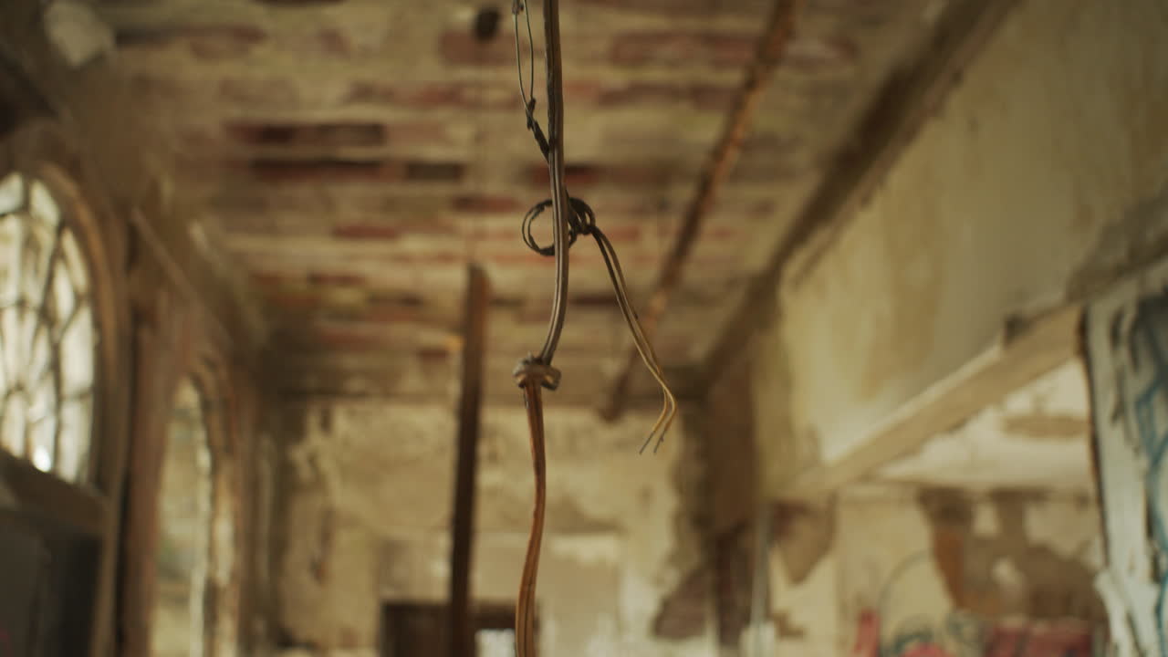 A loose wire swaying gently in an abandoned building