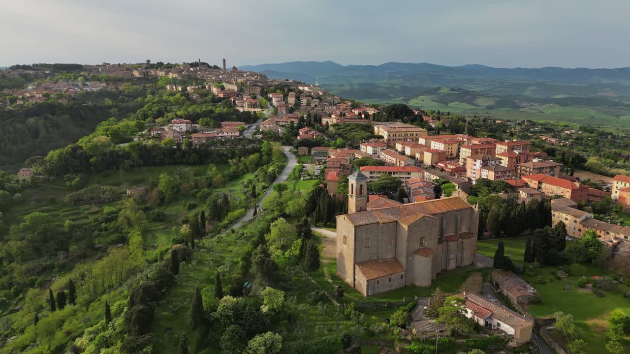 Veduta aerea con drone della città collinare di Volterra, con edifici storici e un paesaggio toscano verdeggiante in Italia.