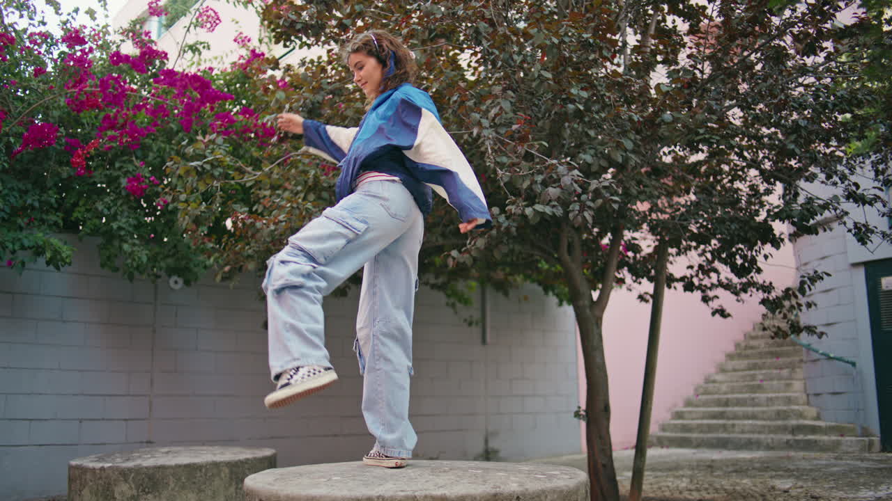 chica adolescente bailando en la plaza urbana con auriculares. mujer tranquila y tranquila disfrutando de la canción