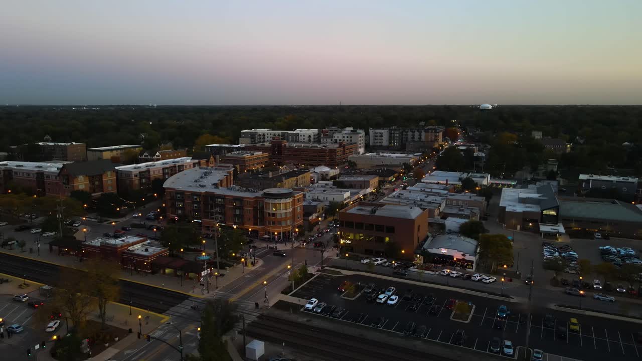 Aerial capture of Downers Grove Illinois at dusk featuring illuminated streets and urban landscape. Crane Up Left Dusk S