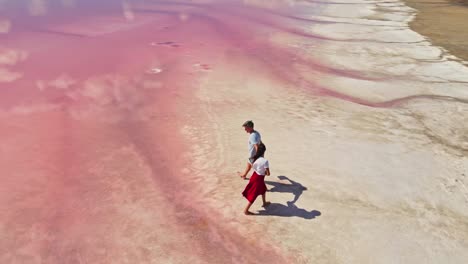 lovely young couple walking along beautiful pink lake with salty shore