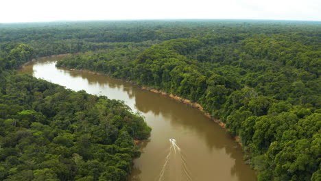 incredible high flying aerial shot of a boat travelling up river in guyana