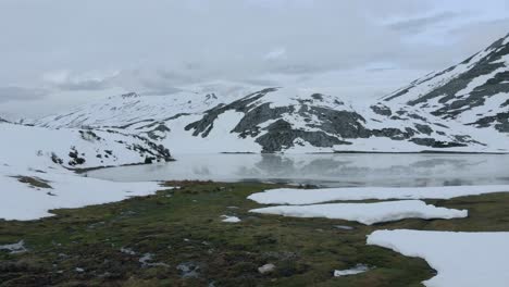 Erstklassige-Drohnenfliege-Aus-Der-Luft-über-Der-Lichtung-Des-Zugefrorenen-Isoba-Sees,-Felsige-Und-Schneebedeckte-Trekkingroute,-Tauwetter-Im-Tal-In-Leon-De-Castile,-Spanien