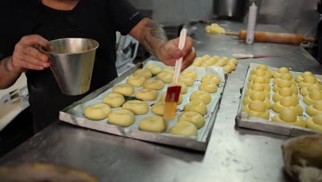 baker preparing pastries with egg wash