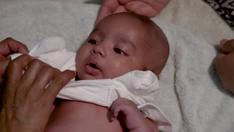 adorable 2 month old indian baby boy being dressed, laying on blanket