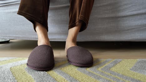 person wearing brown slippers sitting on a couch