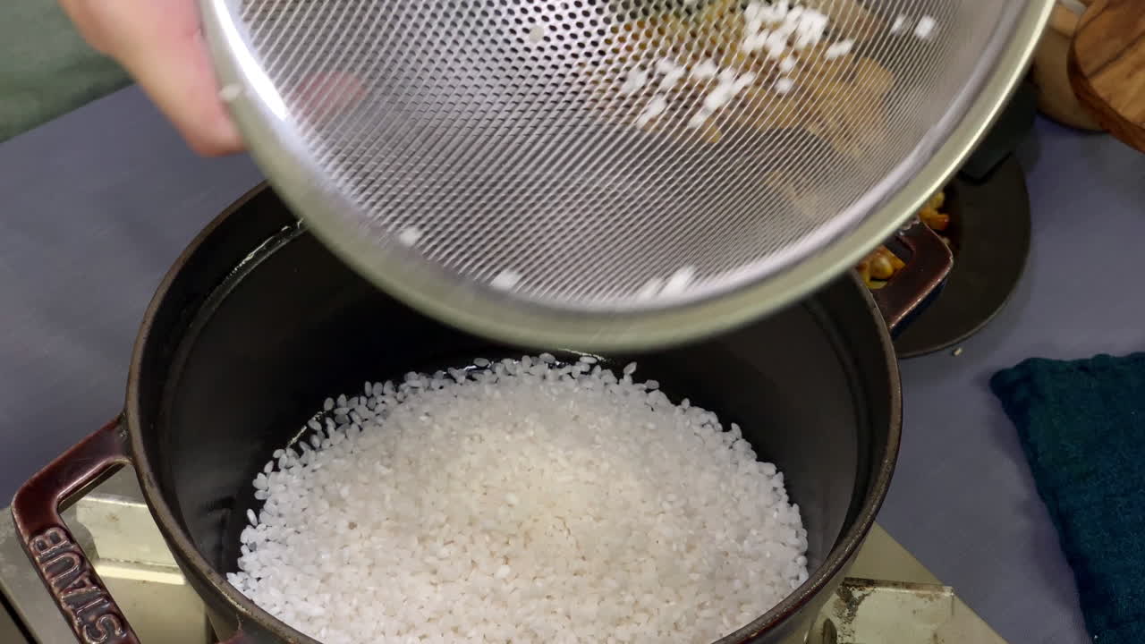 una chef japonesa pone arroz en una olla en la cocina de su casa, tokio, japón