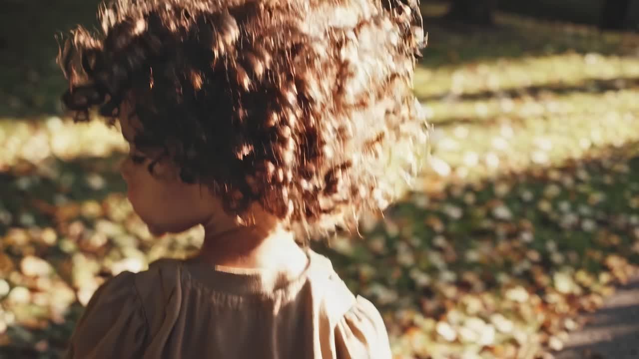 A video captures a child with curly hair in a park, backlit by sunlight