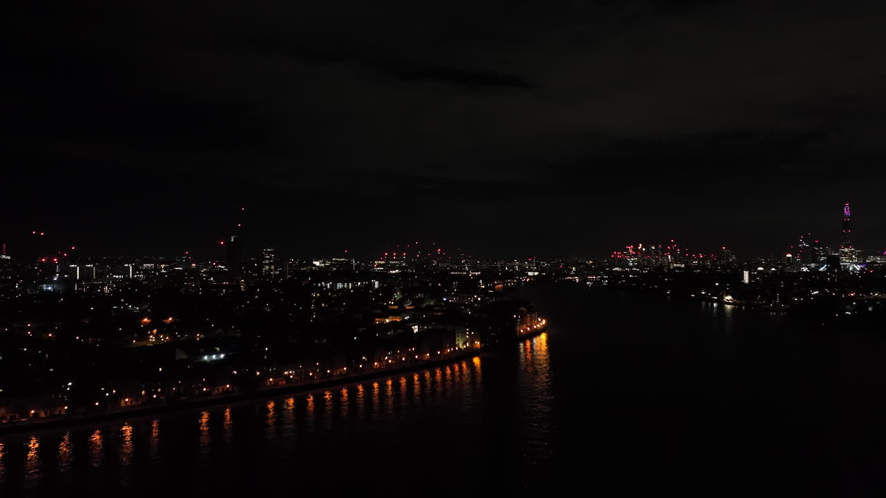 Drone ascending in front of Thames river and Rotherhithe area, night in London