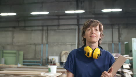 middle aged woman with clipboard in her hands walking alone workshop