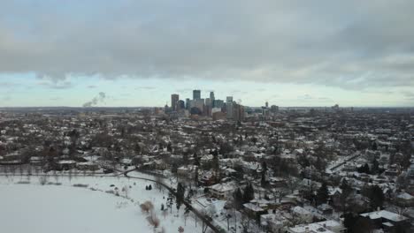 drone flies away from minneapolis skyline, reveals people skating on pond in winter