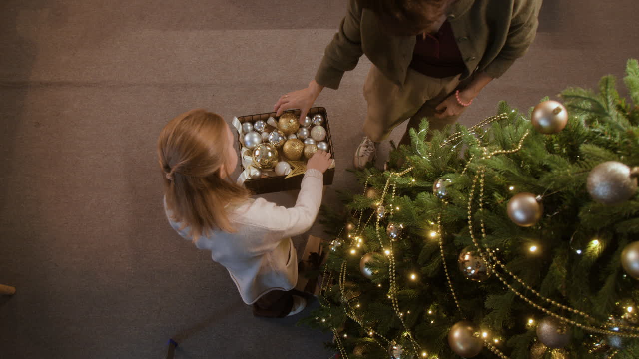 어머니 와 딸 이 크리스마스 트리 를 장식 하고 있다