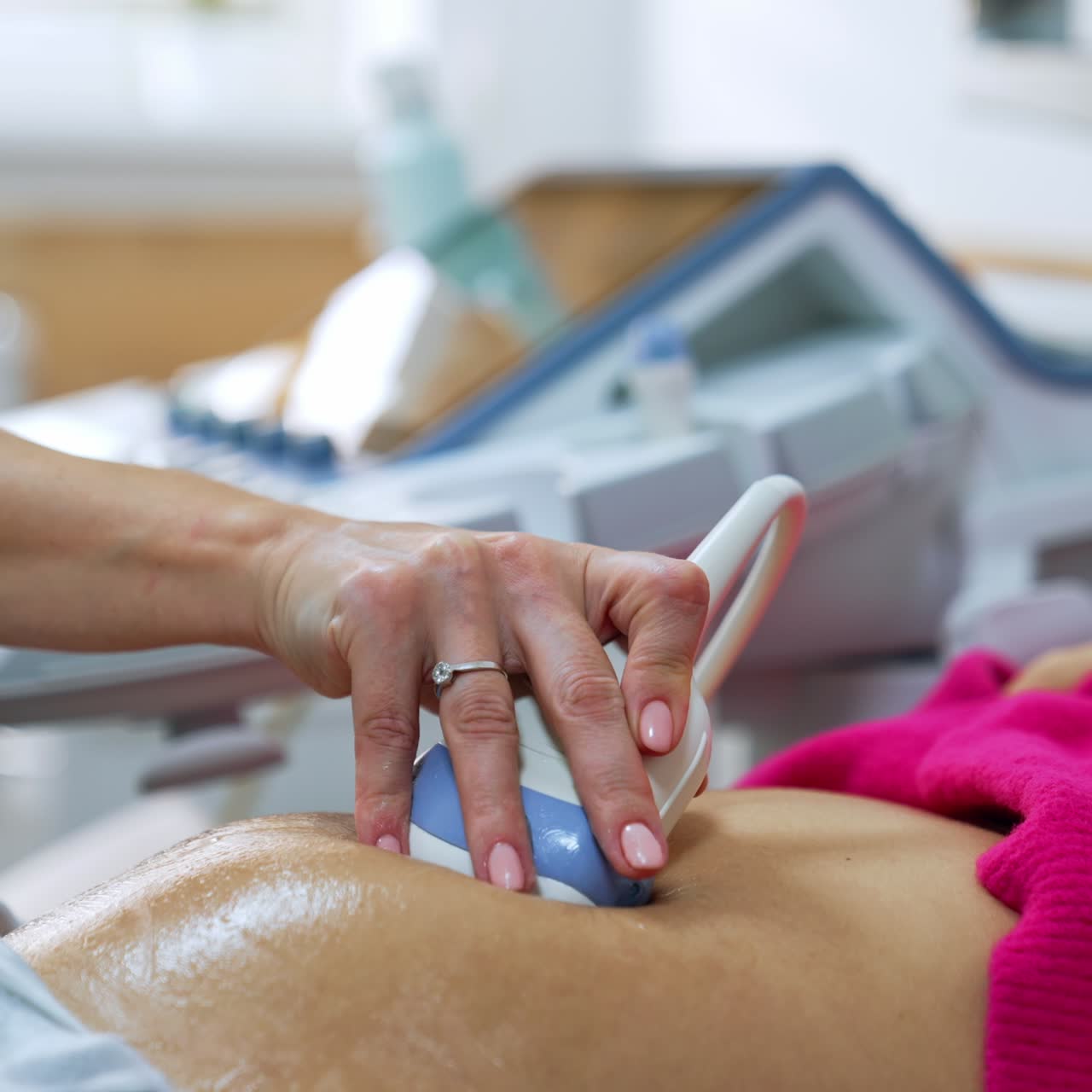 Ultrasound transducer is slowly moved by the pregnant belly of a patient. Intrauterine development of a baby check up