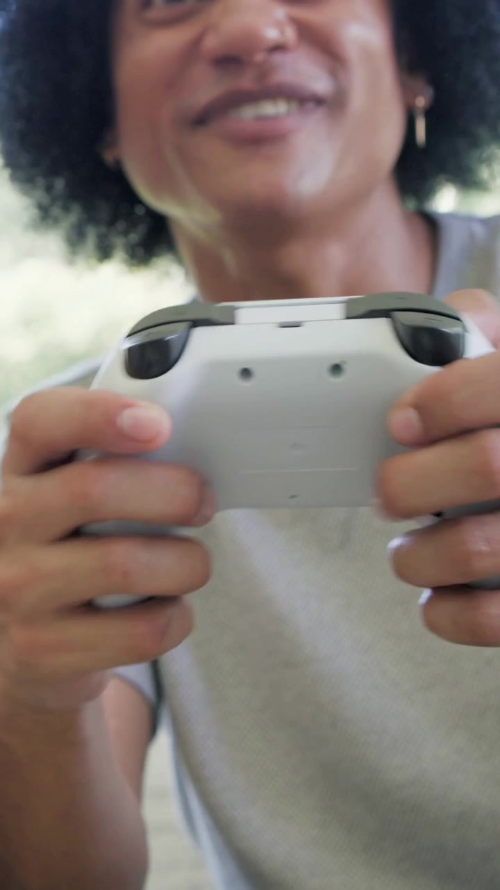 Vertical video: Game starting, man leaning and gripping controller in living room, trying to win