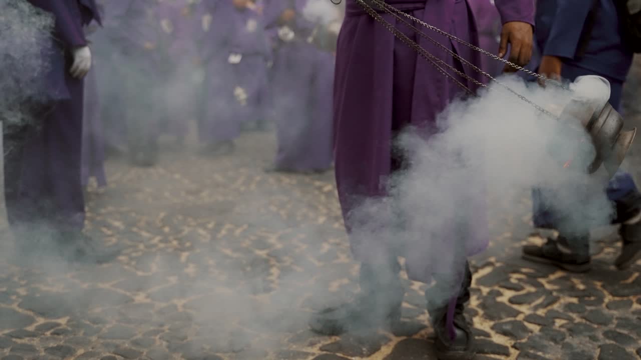 hombres con túnica púrpura echando humo de incienso en la procesión en antigua, guatemala - toma media