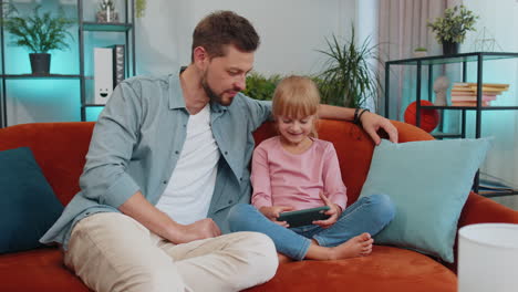 Kind,-Tochter,-Die-Spaß-Mit-Vater-Oder-Kindermädchen-Hat-Und-Es-Genießt,-Mit-Dem-Smartphone-Online-Spiele-Zu-Spielen