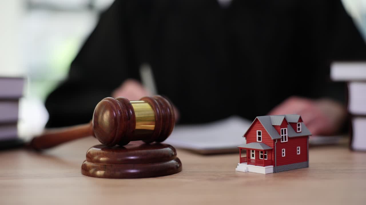 Martello di legno e miniatura di casa giocattolo davanti a un giudice che scrive