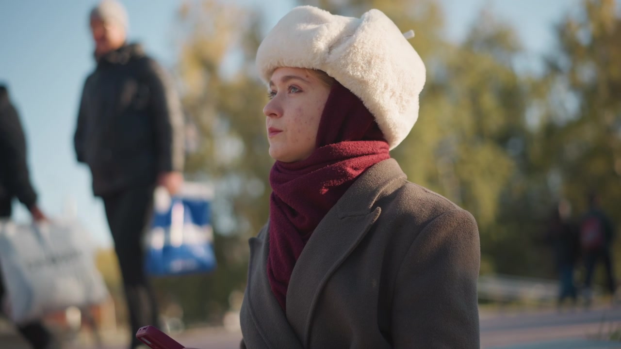 Giovane donna con cappello invernale che usa lo smartphone all'aperto.