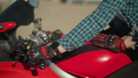 two friends on a power bike, the rider wears a black glove and an led watch, while the passenger wears a blue jean jacket and pink gown, with a blurred background of trees, poles, and parked cars