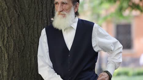 portrait of an elderly man with a beard by a tree