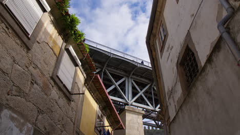 a view under dom luis i bridge with pedestrians across the walkway in porto, portugal. low angle shot