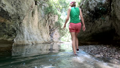 summer adventure concept: woman walks in the water, in a gorge between rocks