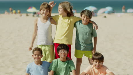 Front-view-of-group-of-friends-posing-for-camera-on-beach