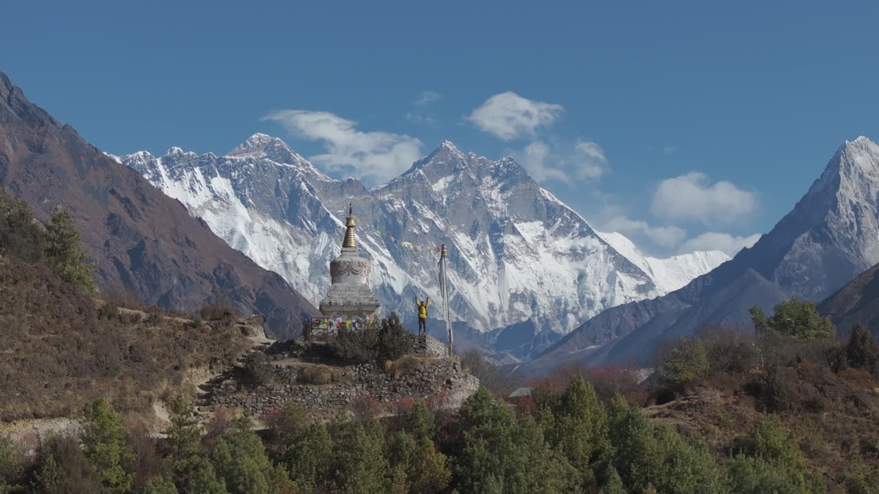 Drone aerial footage of Nepal captures a trekker at Everest Base Camp, enjoying the majestic view of Ama Dablam and Everest from a serene stupa