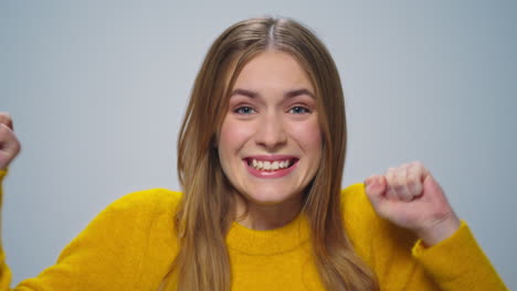 retrato de una mujer positiva disfrutando de la victoria en la cámara sobre un fondo gris.