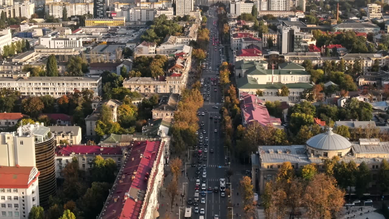 CHISINAU, MOLDOVA - SEPTEMBER 9, 2021: Aerial drone view of downtown at sunset. Panorama view of multiple buildings, the Organ Hall, road with moving cars and lush trees