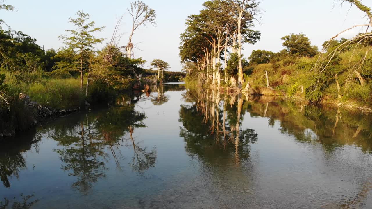 volando 5' sobre un río muy tranquilo al atardecer hacia cipreses