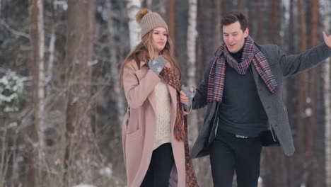 young married couple walks through the winter forest. a man and a woman look at each other laughing and smiling in slow motion.