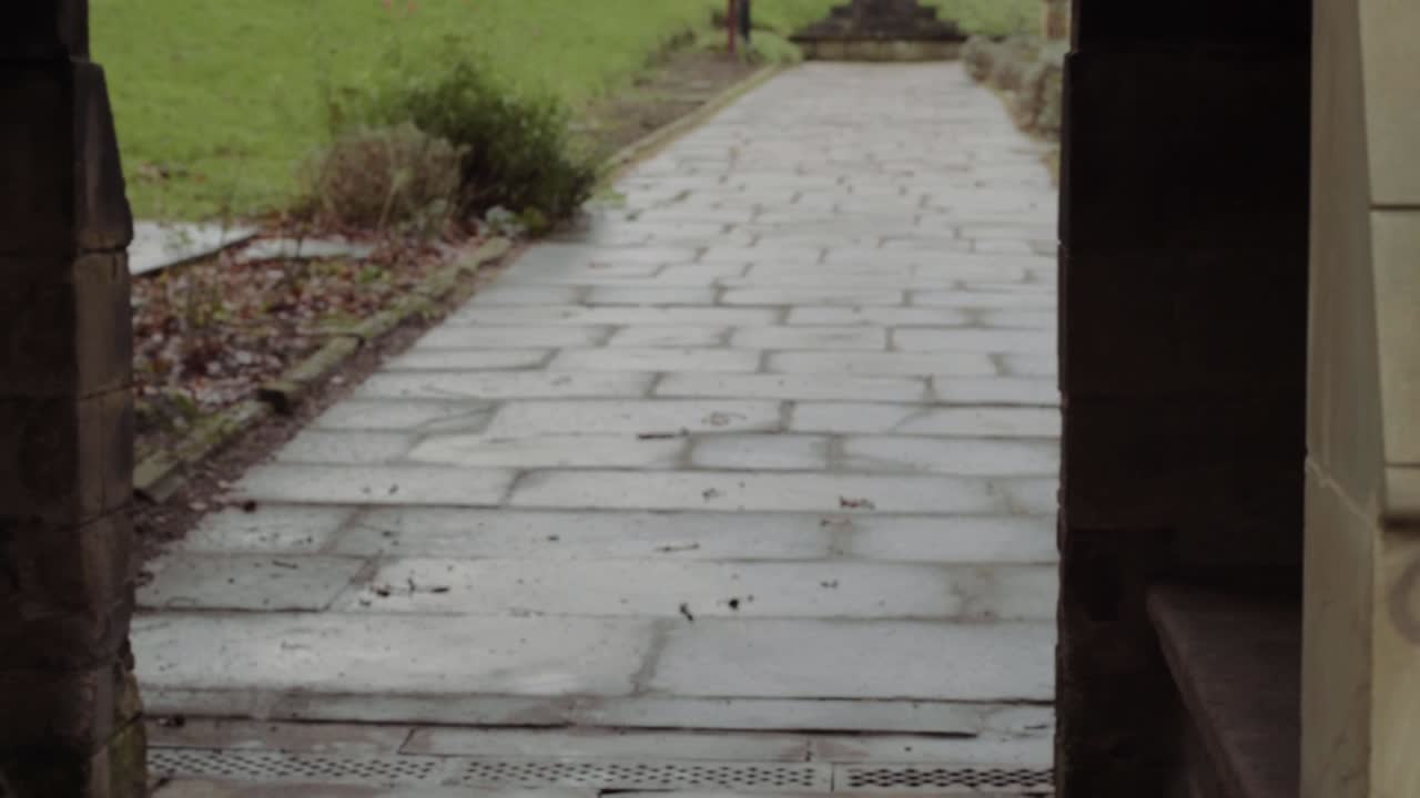 View of church through stone lych gate entrance with wooden seating