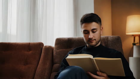 a young man reading a book on a sofa