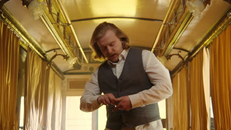 man adjusting vest button in vintage train carriage