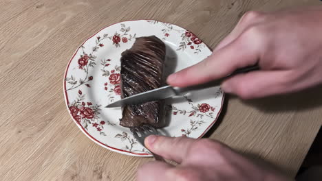 cortar un filete bien hecho con cuchillo y tenedor en el plato de la cocina