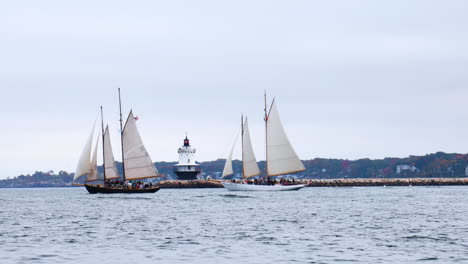 Gorgeous-wide-shot-of-a-pair-of-Schooners-traveling-in-front-of-Spring-Point-Ledge-Lighthouse-in-Casco-Bay,-Maine