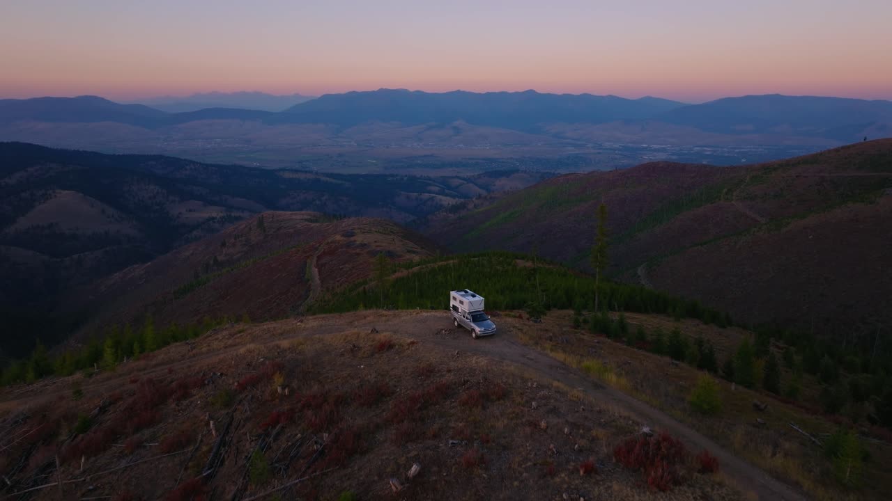 Camper su crinale al tramonto sopra Missoula, Montana, ripresa aerea angolata all'indietro.