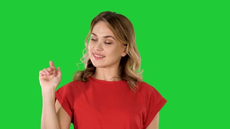 joven mujer caucásica señalando con la mano y el dedo al lado en una pantalla verde, clave de croma