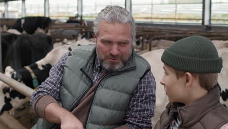 farmer and young person conversing in a dairy barn