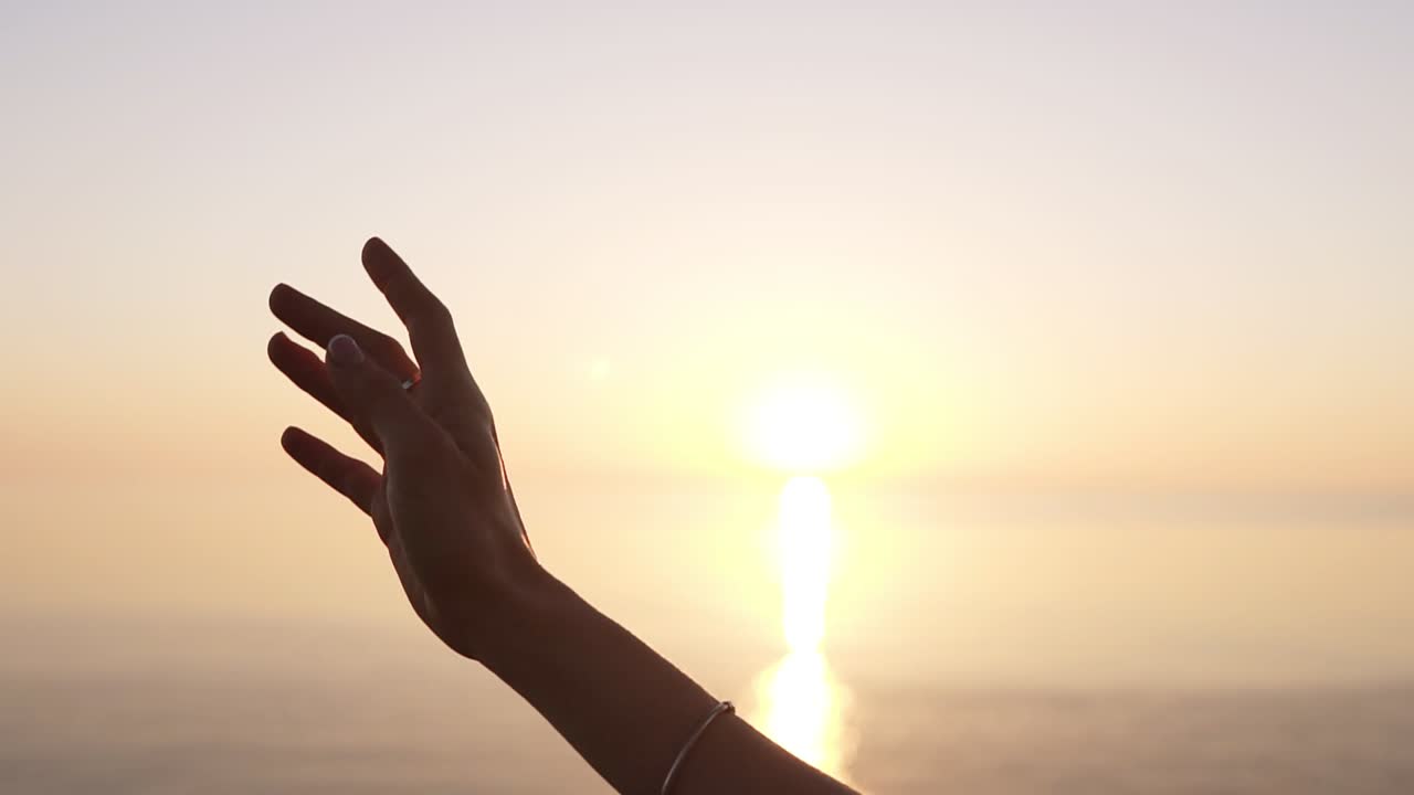 Extremely close up of a woman's elegant hand ascending in ballet performance. Balerina in black tutu. Outdoors. Sunlight. Slow motion