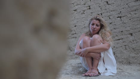 panning revela una foto de una mujer vestida de blanco agachada entre las antiguas ruinas griegas