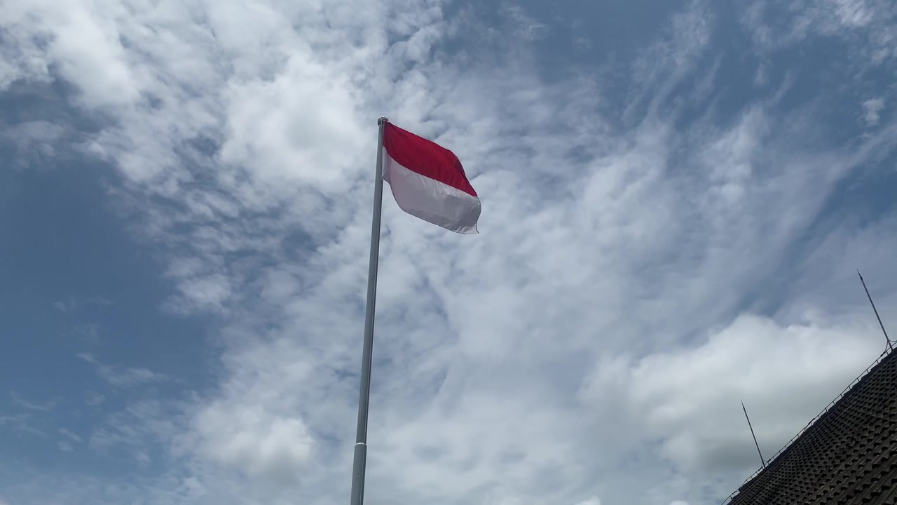 Bandeira da Indonésia tremulando em um mastro alto contra um céu nublado dramático