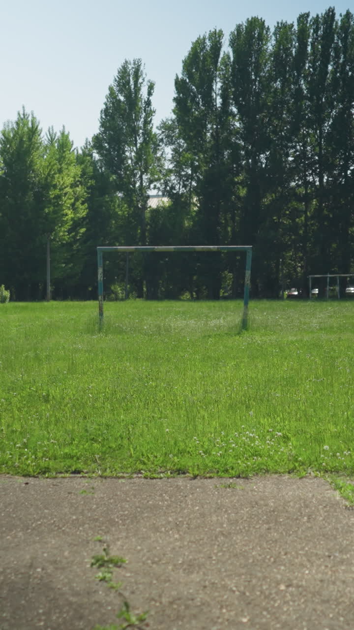 Four siblings are actively playing football on a paved road, with one kicking the ball while others engage in the game