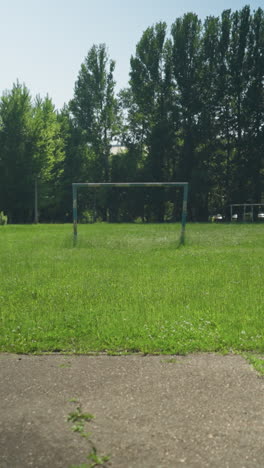 four siblings are actively playing football on a paved road, with one kicking the ball while others engage in the game