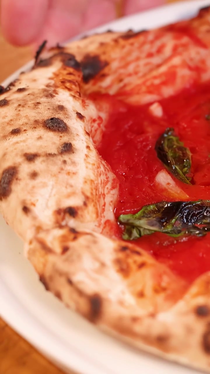 Primo piano dettagliato di una pizza marinara gourmet che ruota lentamente su un piatto bianco.
